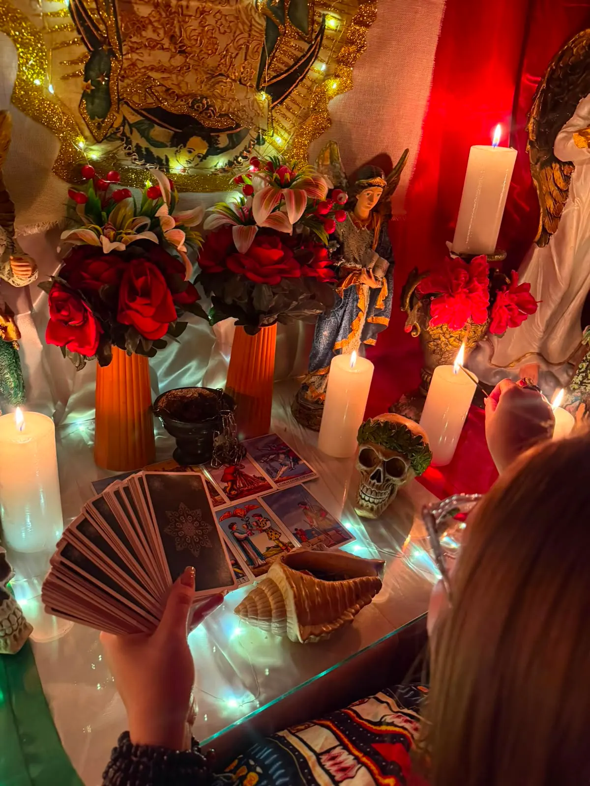 Altar con la Virgen de Guadalupe, rosas rojas y velas encendidas mientras se barajan las cartas para una consulta