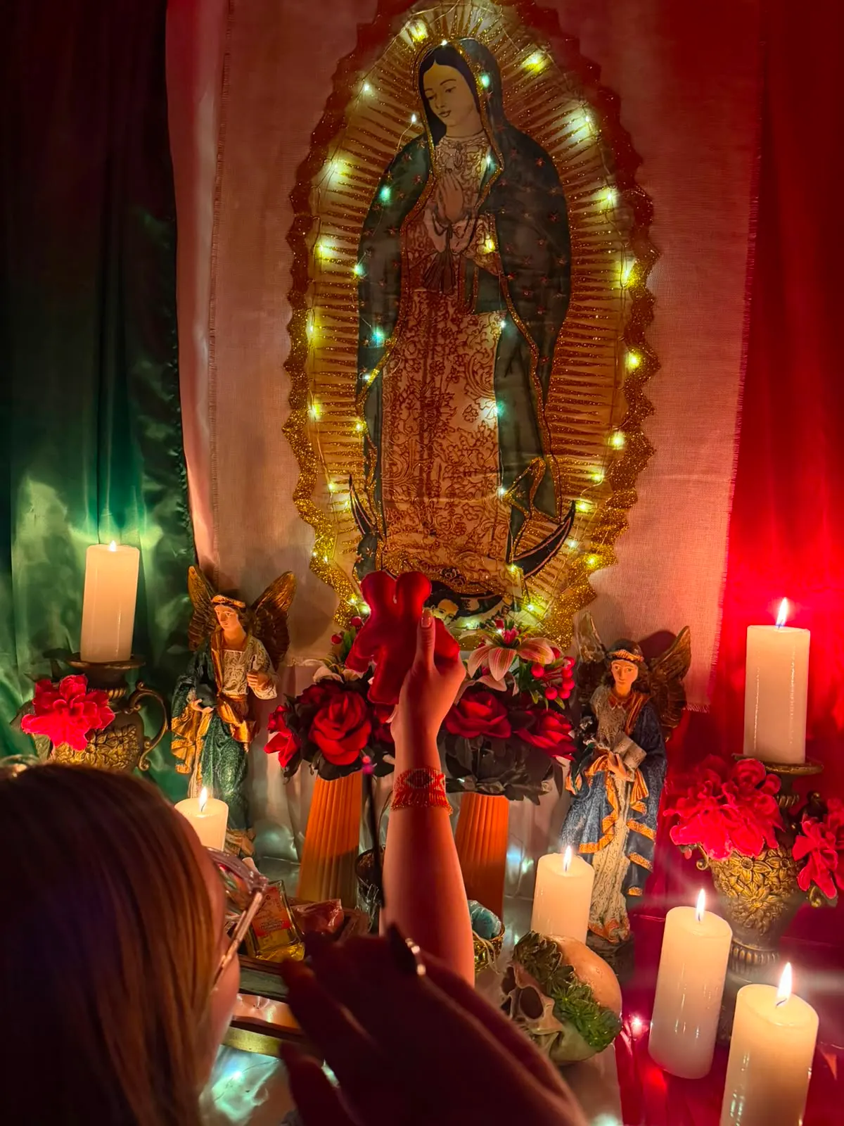 Manos colocando rosas rojas frente a la Virgen de Guadalupe durante la preparación de un amarre de amor