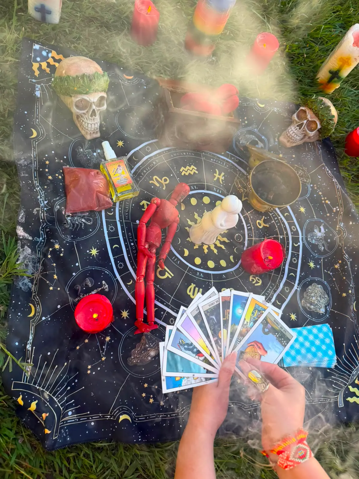 Humo de sahumerio sobre una ofrenda con velas, figuras y cartas durante una limpia